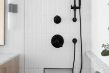 a chic bathroom with white skinny tiles, a niche shelf with black edge for storage, black fixtures