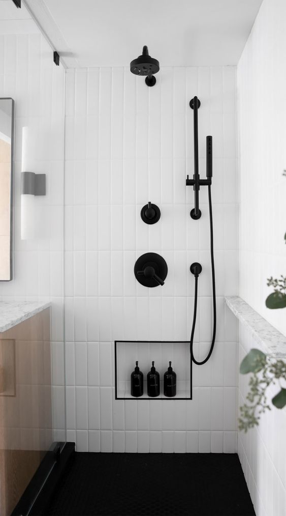 a chic bathroom with white skinny tiles, a niche shelf with black edge for storage, black fixtures