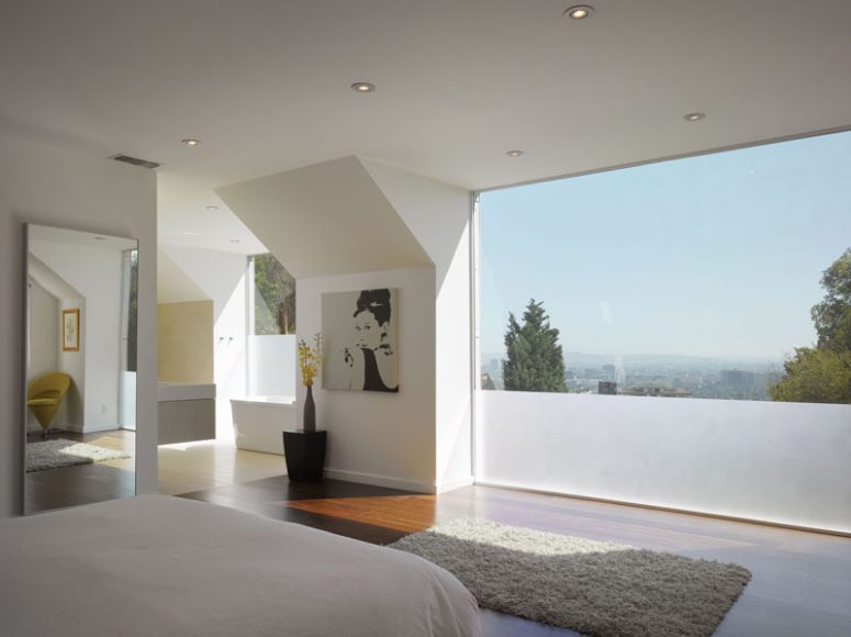 a contemporary bedroom with a laconic interior and a panoramic window with partial frosting to keep it more private