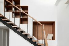a contemporary space with a skylight, a staircase with stained steps and niche shelves for storing books and for sitting