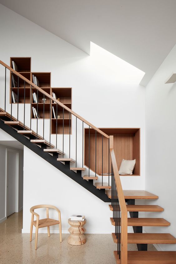 a contemporary space with a skylight, a staircase with stained steps and niche shelves for storing books and for sitting