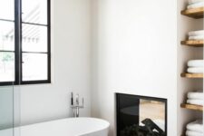 a contemporary white bathroom with a beige tile floor and a fireplace, with a niche with wooden shelves is cool