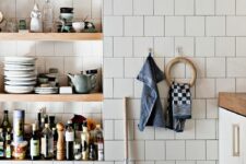 a kitchen clad with white square tiles and with niche shelves that are used instead of cabinets to store everything needed