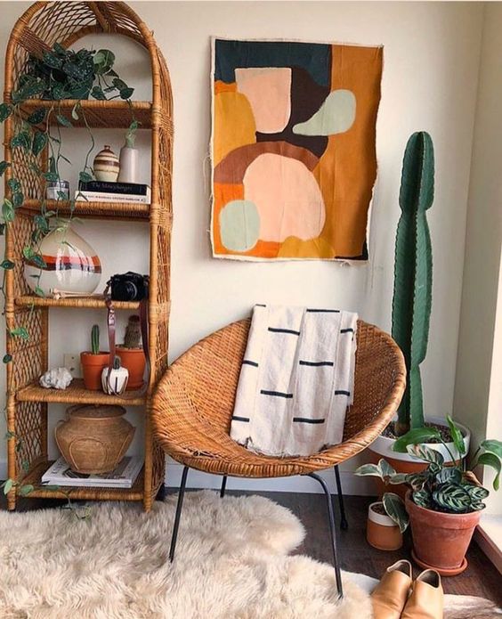 a mid-century modern nook with a wicker arched shelving unit, a round wicker chair, potted plants and a cactus, bold art and rugs