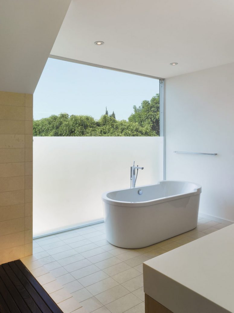 a minimalist neutral bathroom with a panoramic window, partly with frosting to enjoy the views but keep the space private