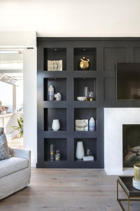 a modern living room featuring a fireplace and a series of niche shelves for displaying various decor