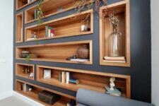 a modern living room with a graphite grey accent wall dotted with stained wood niche shelves used as a large display