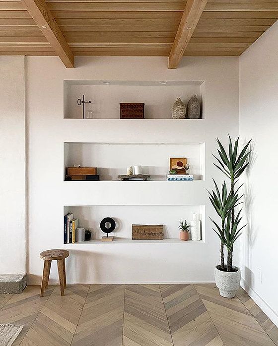 a modern space with a wooden ceiling with beams, a parquet floor and three niche shelves for storing stuff