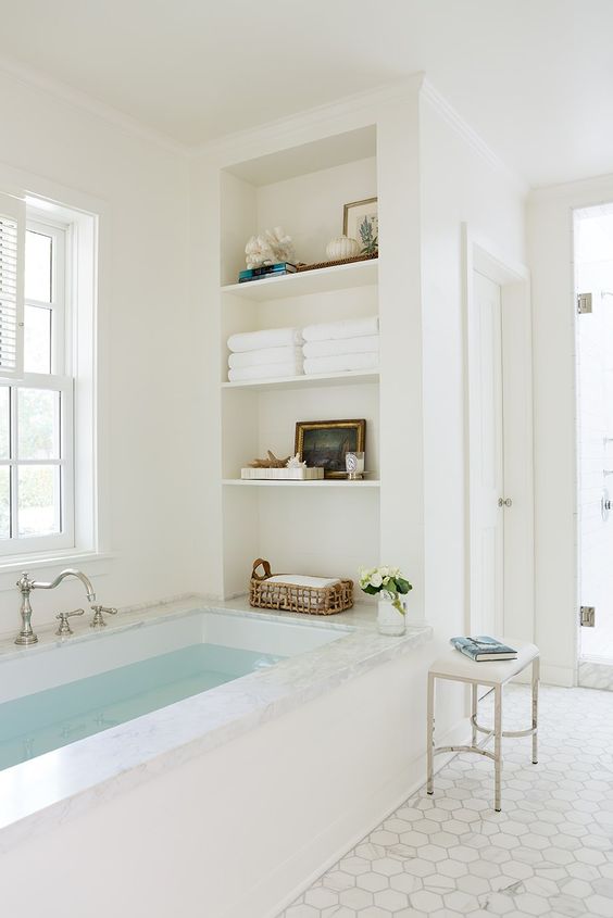 a neutral airy bathroom with a bathtub and niche shelves by its side is a cool idea, there you can store anything you want