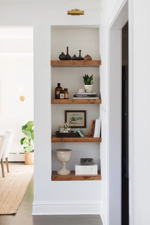 a small awkward nook by the doorway taken by niche shelves with various cool accessories and plants is a great idea to rock