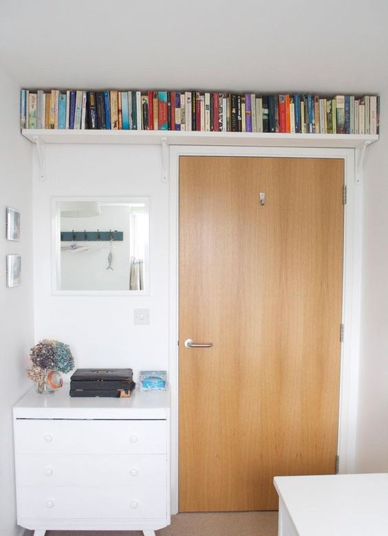 a small bookshelf over the doorway allows to store a lot of books and not to clutter the small space at the same time