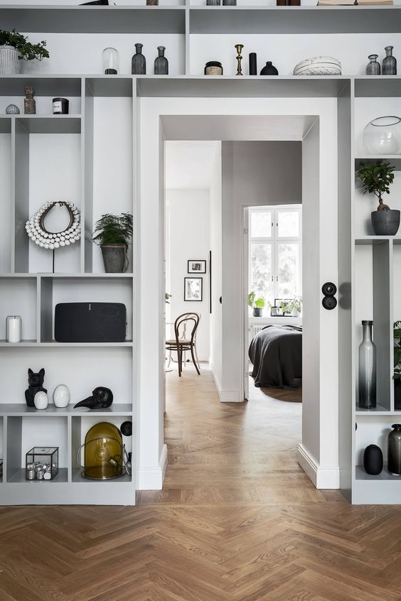 all the space around the doorway take by an open shelving unit display art, candleholders, potted plants and various accessories