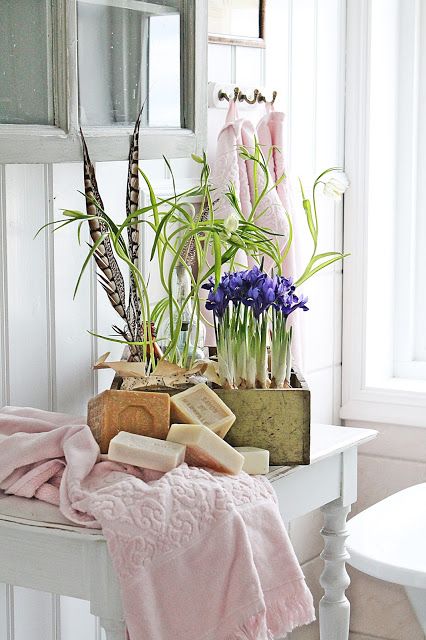 cool Scandinavian bathroom decor with a box with bulbs and greenery, feathers and stacks of soap pieces