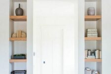 long and narrow niches with wooden shelves inside add decorative value to the space and show off some stuff inside