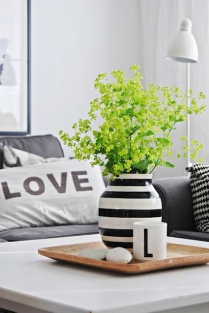 simple and cool Scandinavian decor with a wooden tray with pebbles, a mug and a striped vase with green blooms