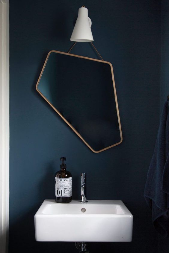 a beautiful and asymmetrical mirror in a copper frame is a catchy idea for a bathroom or a powder room, it will add interest to it