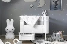 a beautiful grey nursery with a sky theme, paper pompoms and a stuffed cloud, moon and star