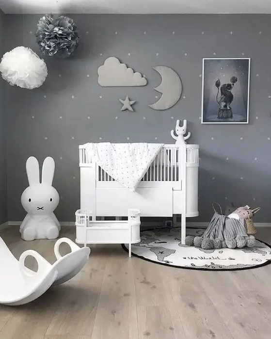 a beautiful grey nursery with a sky theme, paper pompoms and a stuffed cloud, moon and star