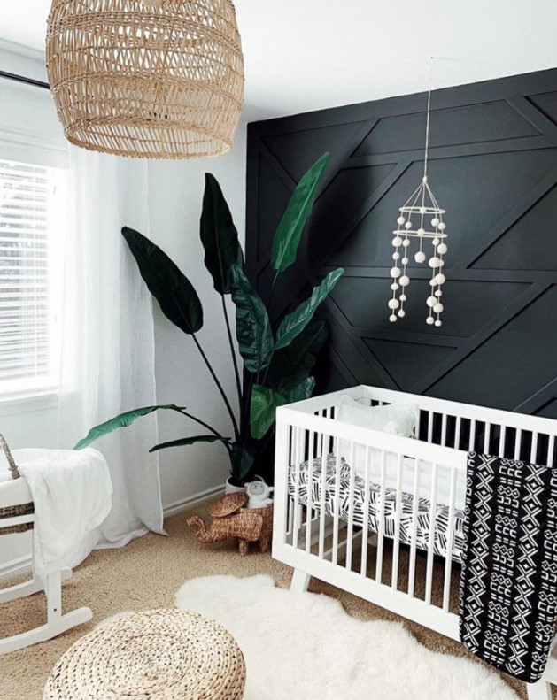 a boho nursery with a black geometric accent wall that stands out and make the whole space more stylish