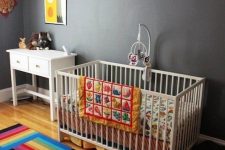 a bold nursery with grey walls but striped rugs, colorful buntings, colorful bedding and artworks for fun