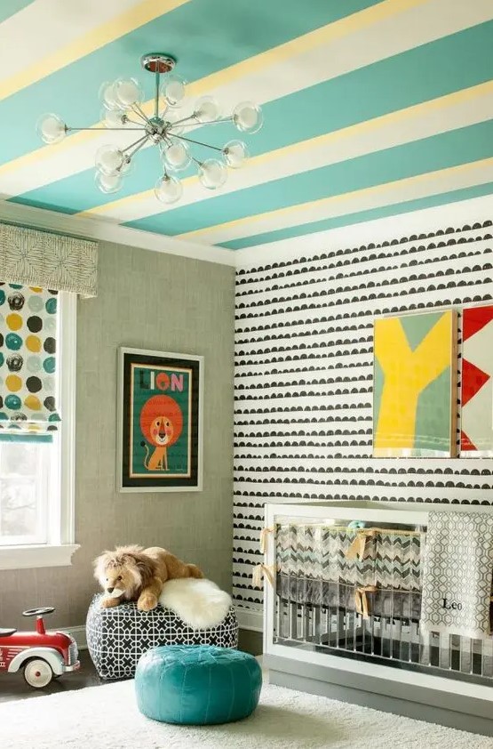 a bright mid century modern nursery with a yellow and turquoise striped ceiling, an accent wall, an acrylic crib, poufs, bright artwork
