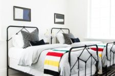 a bright shared boy bedroom with white walls, black beds, layered rugs and bright graphic bedding
