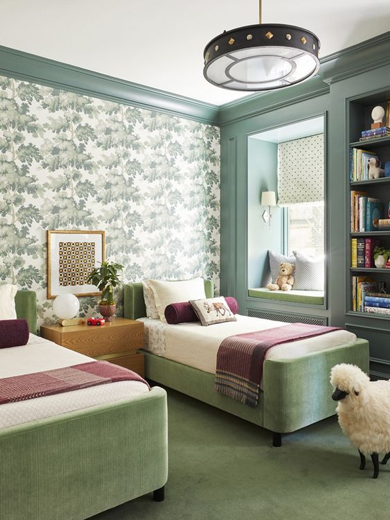 a chic and stylish modern shared room with a botanical print accent wall, green upholstered beds, printed bedding, a built-in bookshelf and a window seat