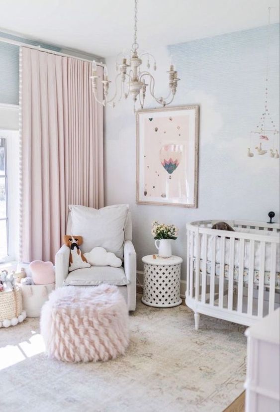 a chic girlish nursery with light blue walls, white furniture, blush textiles, a lovely artwork and a vintage chandelier