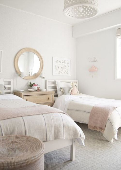 a chic neutral shared bedroom with white beds and a stained dresser, neutral and pink bedding, a mirror in a wooden frame, a white pendant lamp and a basket for storage a chic neutral shared bedroom with white beds and a stained dresser, neutral and pink bedding, a mirror in a wooden frame, a white pendant lamp and a basket for storage