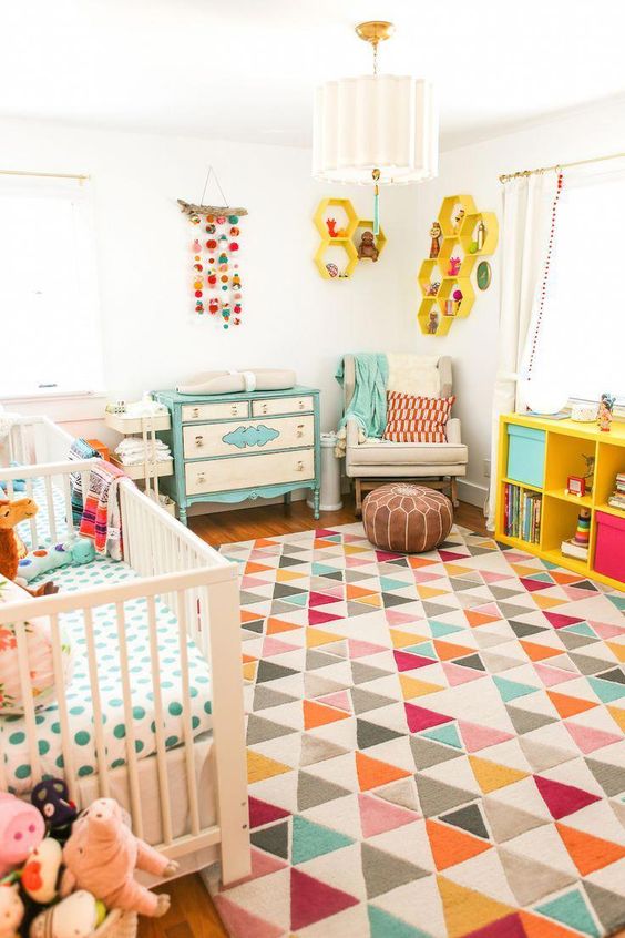 a colorful nrusery with a mint dresser, colorful bedding and textiles, bold honeycomb shelves on the wall