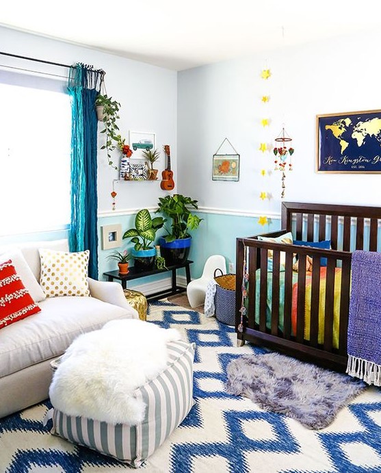a colorful nursery with a printed rug, bright blue curtains, bedding and colorful pots and mobiles