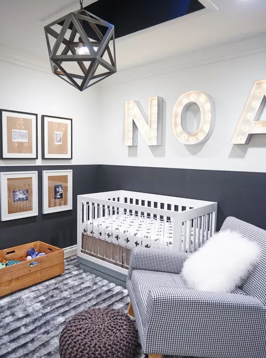 a contemporary grey and white nursery with a faceted pendant lamp, marquee letters, a mini gallery wall, a white wood and clear acrylic crib, a printed chair