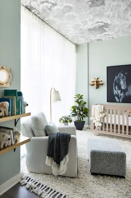 a contemporary light green nursery with a cloud ceiling, a neutral crib, a neutral chair with a footrest, floating shelves and potted plants