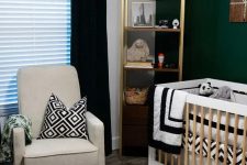 a contrasting mid-century modern nursery with a dark green accent wall, a gold shelving unit, a neutral crib, a grey chair, a black pouf and black and white textiles