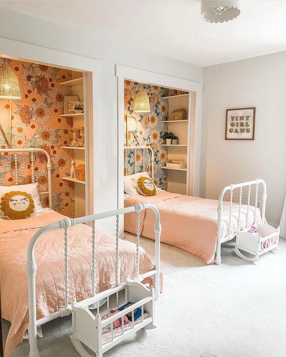 غرف بنات مشتركة A-cool-shared-girls-bedroom-with-niches-done-with-floral-wallpaper-and-shelves-white-metal-beds-little-play-cribs-and-pink-bedding