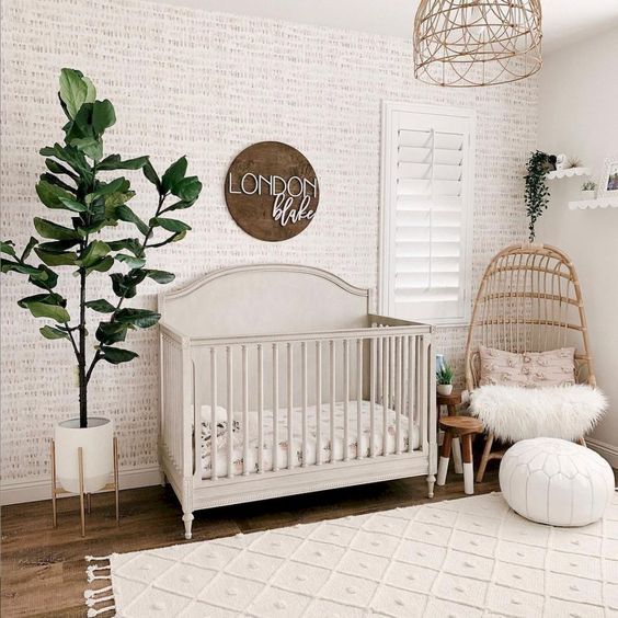 a cozy modern nursery with wallpaper walls, a sign, wicker chairs and a lampshade, potted greenery