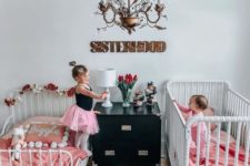 a cute black and white shared room with white beds, pink bedding and whimsy and chic details