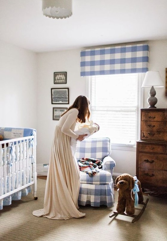 a cute farmhouse nursery with lot sof blue plaid, a stained dresser, a neutral rug and a white vintage crib