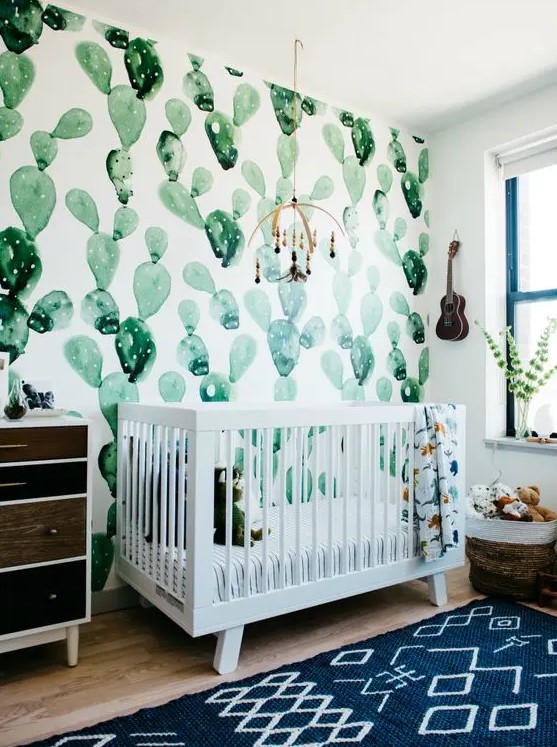 a desert-themed nursery with a watercolor cactus wall, a reclaimed wood dresser is a cool and bright space
