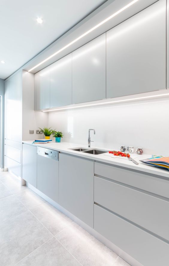 a dove grey minimalist kitchen with sleek cabinets, white stone countertops and a white glas sbacksplash is a delicate and chic space