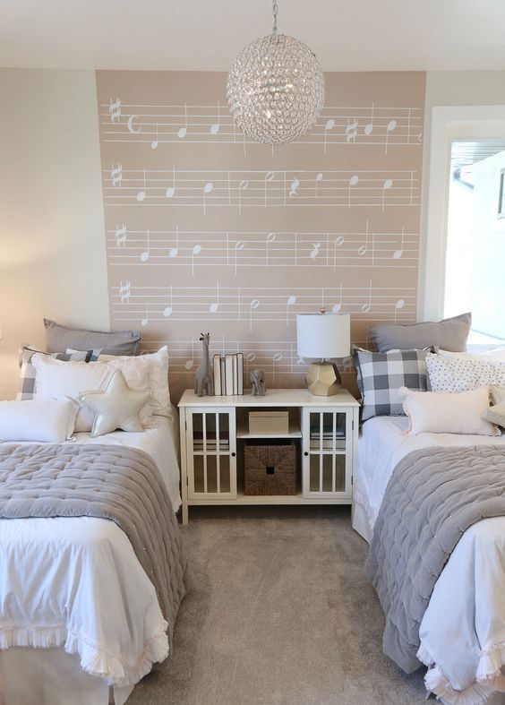 a dreamy neutral shared girls' bedroom with white beds and a storage unit, grey and white bedding, a music accent wall, a crystal pendant lamp a dreamy neutral shared girls' bedroom with white beds and a storage unit, grey and white bedding, a music accent wall, a crystal pendant lamp