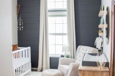a farmhouse nursery done with a cute mobile, a printed ottoman and a faux animal skin as boho touches