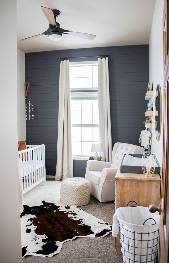 a farmhouse nursery done with a cute mobile, a printed ottoman and a faux animal skin as boho touches