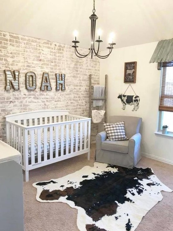 a farmhouse nursery with a whitewashed brick wall, an animal skin rug, grey furniture and a vintage chandelier