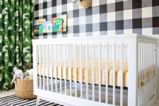 a fun tropical nursery with a mix of prints – a plaid statement wall, a striped rug and a tropical leaf print curtain