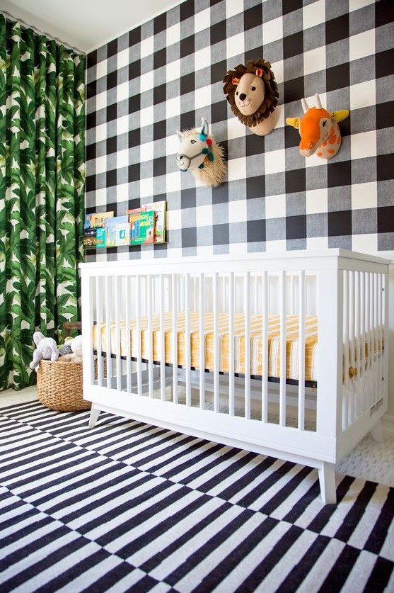 a fun tropical nursery with a mix of prints   a plaid statement wall, a striped rug and a tropical leaf print curtain