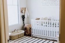 a gorgeous boho nursery with a white crib, a star mobile, a tassel chandelier, a leather ottoman and layered rugs