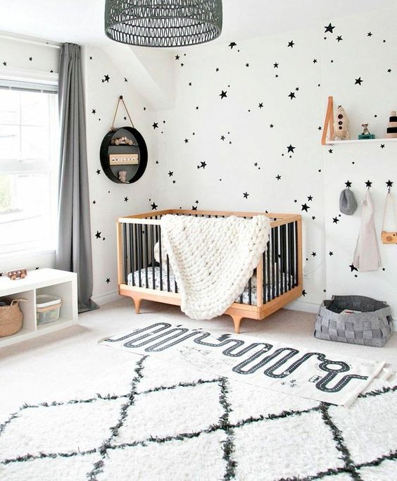 a gorgeous contemporary nursery done in black and white, with star print wallpaper, a printed rug, neutral furniture