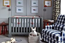 a lovely grey nurseyr with a grey crib, a plaid rocker chair, layered rugs, a bold gallery wall and a basket with toys