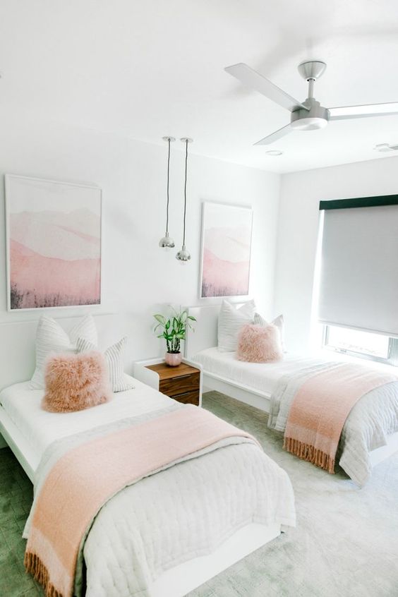 a lovely shared girls' bedroom with white beds and a stained nightstand, pink and neutral textiles, pink artworks